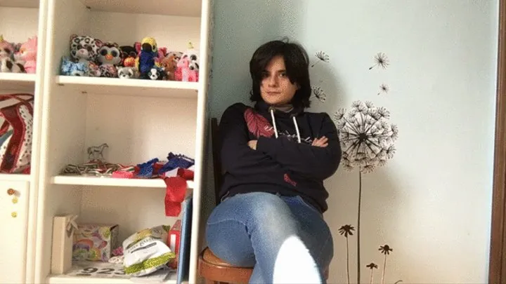 I sit cross-legged on a wooden chair wearing jeans