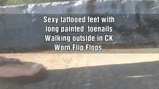 Sexy tattooed feet with long painted toenails Walking outside in CK well Worn Flip Flops