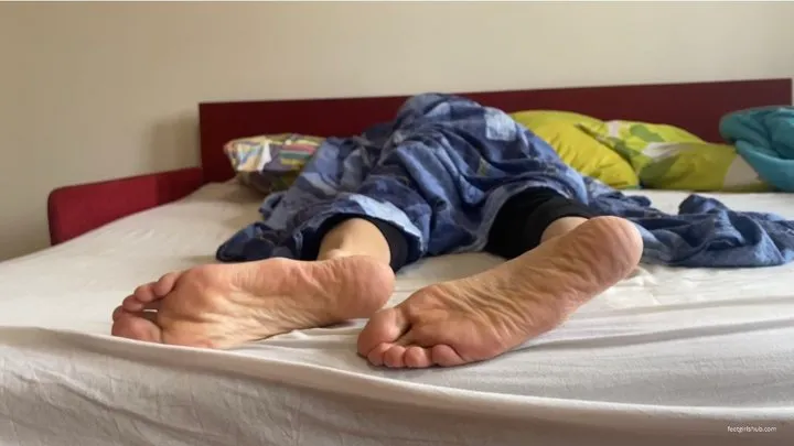 WOMAN'S FEET UNDER THE BLANKET SNORING IN BED