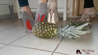 Two mistresses crushing a pineapple in high heels