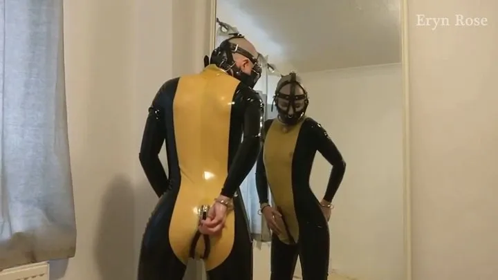 Muzzled slave in tight latex catsuit