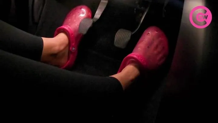 Woman driving and pedal pumping manual car, barefoot and wearing pink transparant crocs