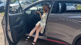 A girl in high-heeled shoes presses the pedals of her car and enjoys the sounds of the car engine