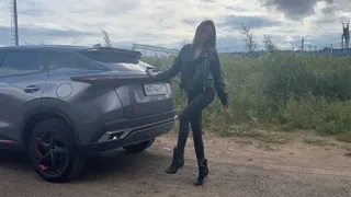 A girl in leather boots presses the pedals of a car, enjoys the sound of the engine and plays with her feet with the dashboard