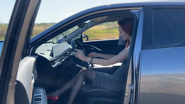 A girl in a car is stuck in a field, the car won't start and the girl doesn't know what to do