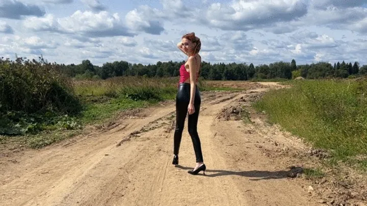 A girl in high-heeled shoes walks down the street and finds deep and sticky mud where she dips her shoes with pleasure