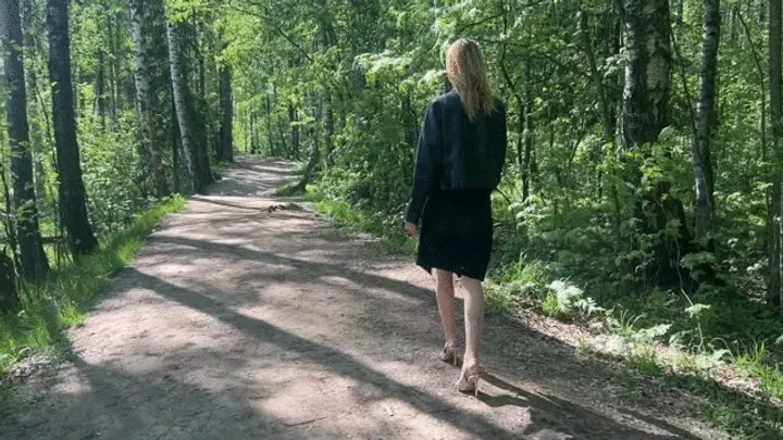 A girl in high-heeled shoes walks along a forest path and stumbles over an irregularity, she falls and causes pain, it seems now she will have to walk with a sprained ankle