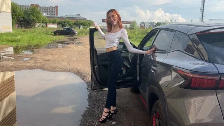 girl in high heels plays in the car with heels, presses the car pedals and rubs her heels on them, then goes about her business without taking off her high heels