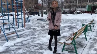 girl having fun on the playground in a summer dress and tights in the snowI