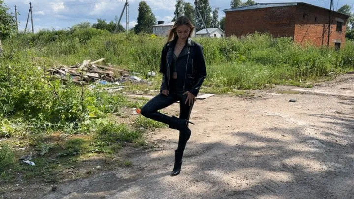 girl in leather boots with high heels walks through the mud