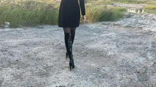 girl in high-heeled leather boots walks through the swamp, her boots get wet