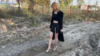girl in mules in high heels walks through the mud and gets her feet dirty