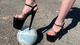 a girl in extremely high heels (30 centimeters) plays football on the street, tries to run after the ball, but it is very hard and she constantly falls