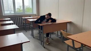 a girl sits at lesson in school and plays with her feet and ballet shoes