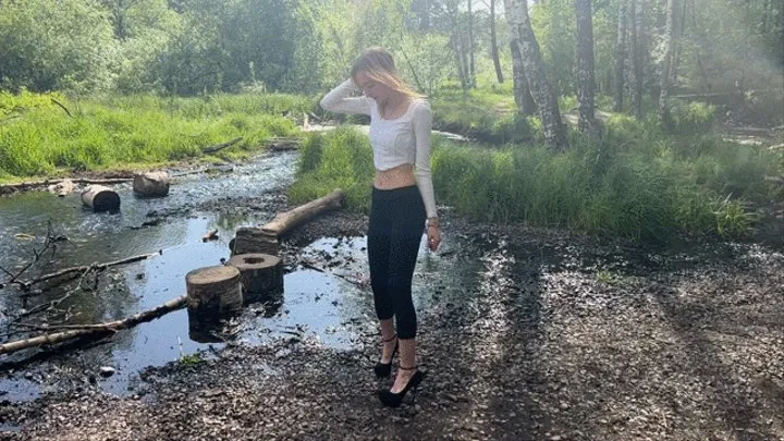 girl walks through the swamp in high heeled shoes, water flows inside the shoes along with the sand that comes out of the shoes