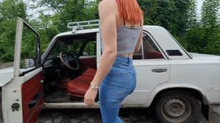 Redheaded Anya cranks an old car with a red leather interior, starts it up and pedal pumping