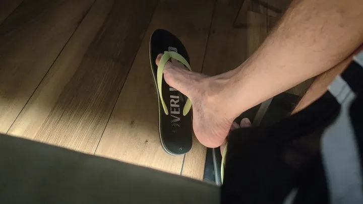 Long and skinny male feet dangling flip flops