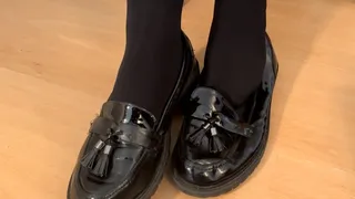 Shoeplay and dangling in black flat loafers and Doc Marten shoes with black pantyhose