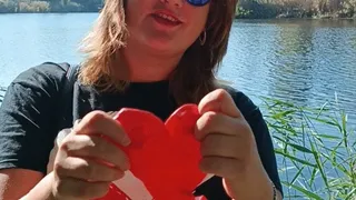 blowing big red heart ballon on the river