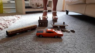 GIANTESS Charn crushes buildings, small cars a train coach and a Plymouth car in chunky white high heels closeup view feet foot toy car crush