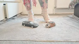 Jayne Vs Volvo V70 & classic mini toy car crush in snakeskin heels with painted toe nails ground view