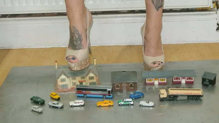 Giantess Atari Queen destroys and crushes tiny toy cars, bus, truck and buildings in high heels closeup ground view