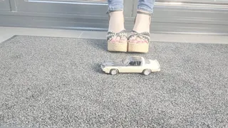 Ground view Abby crushes a 1980s Chevrolet Camaro in chunky denim sandals