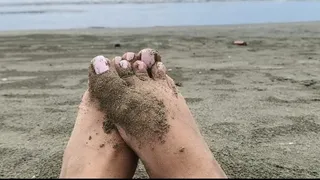 Feet in the sand in front of the sea