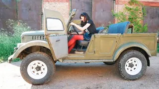 Long-legged beauty in red tights drives and pedal pumpung old Soviet jeep Gaz-69