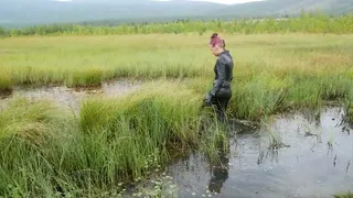 Pretty girl in leather leggings discovers swamp mud, walks, falls and gets stuck in swamp mud