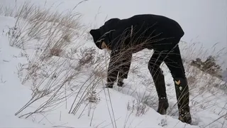 Girl in high heels falls down and tries to climb a snowy mountain