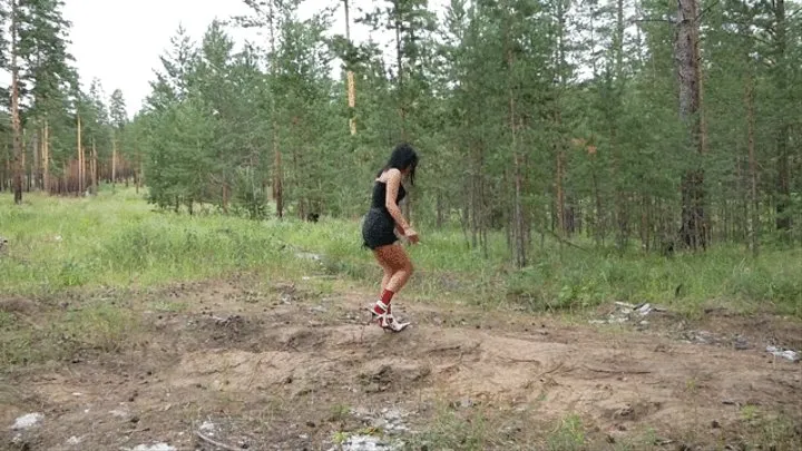 Hot girl in high-heeled boots smoking and walking on sand and falling through sand