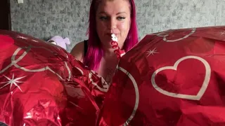 Girl blowing foil hearts balloons