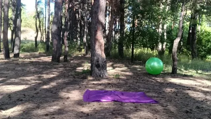 girl jumping on green ball in forest