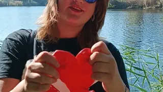 girl in park blow big red heart