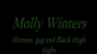 Molly Winters blindfolded, harness gag in black thigh highs