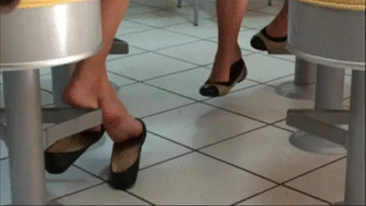 Two girls barefoot shoeplay on barstools