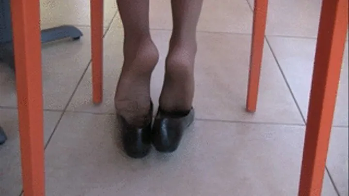 Black flats with nylons under chair from rear