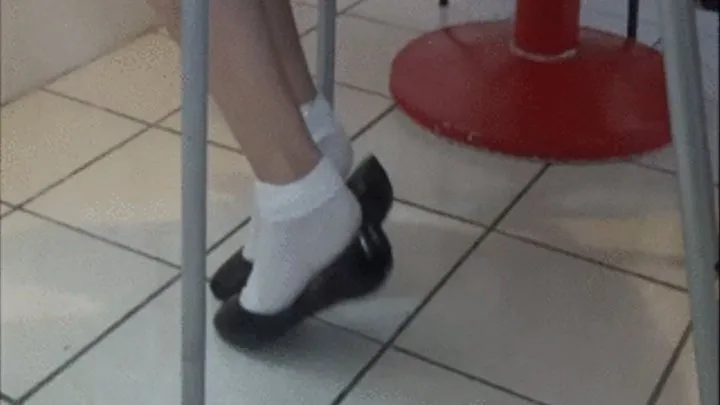 2 girls playing footsie under chair with flats