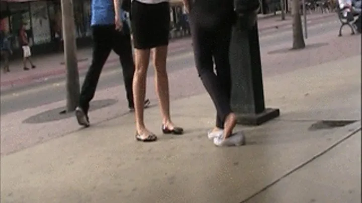 2 girls in flats & nylons standing at a phone booth 2