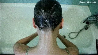 On knees out of the bathtub with hose on hair.