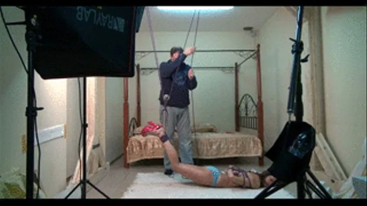 Ekaterina suspended by her feet upside down on-screen