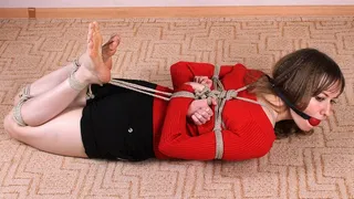 Ballgagged barefoot Agnes in red sweater and black shorts, hogtied with hemp rope, struggles on the floor