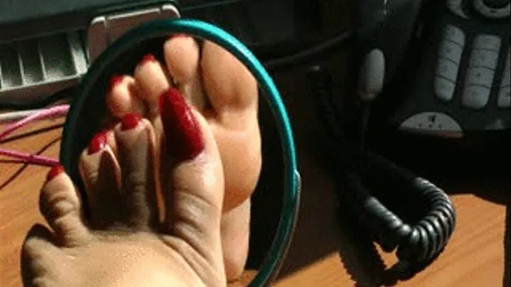 Toewiggling left foot with dark red painted toenails in the little mirror