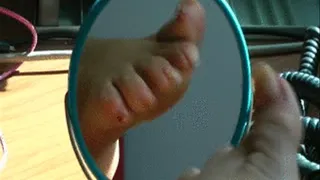 Toewiggling left foot with unpolished toenails in the little mirror