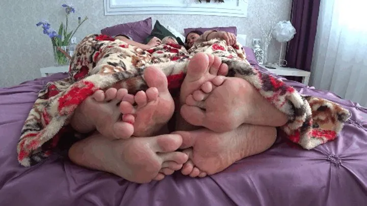 Three pairs of legs flirting under the blanket aF