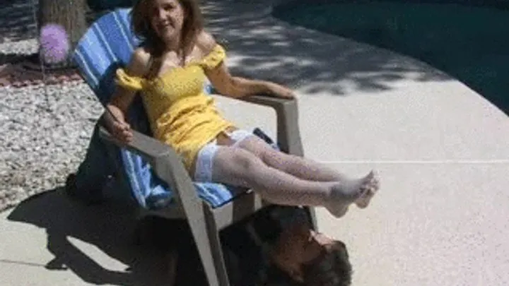 Mistress Brandie relaxes at the pool side and has her slave down under her chair where she smothers her stockings feet all over his face to amuse herself