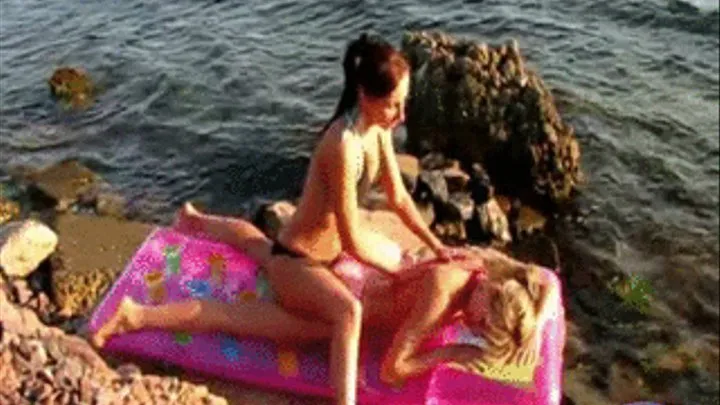 2 girls on beach oiling each other on mattress