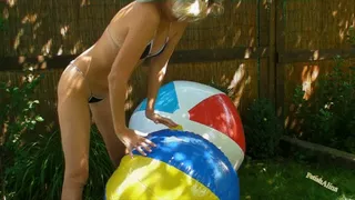 Deflating beach ball outdoors in black bikini