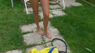 Pumping up a beach ball with rubber foot pump in black bikini